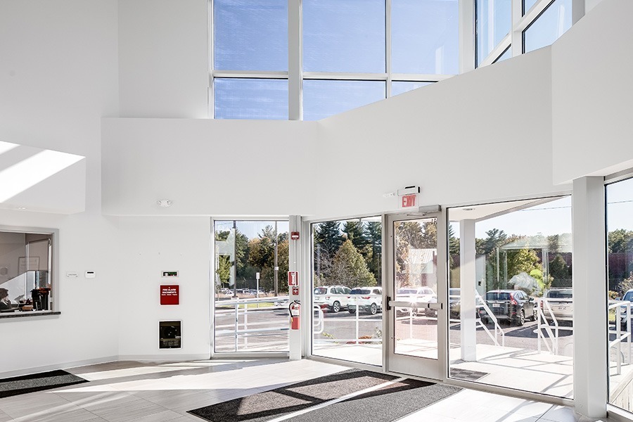 Bright commercial building lobby with glass entry doors and large windows allowing natural light.